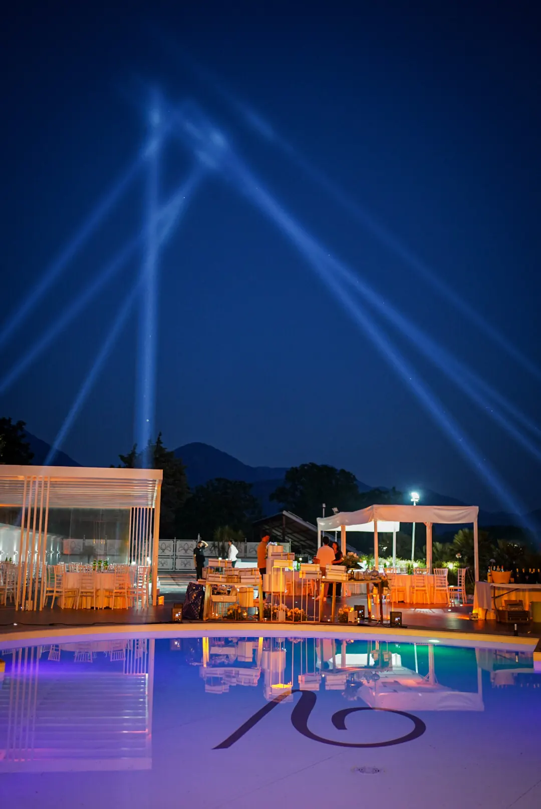 Fasci di luce geometrici nel cielo di notte, sopra una piscina