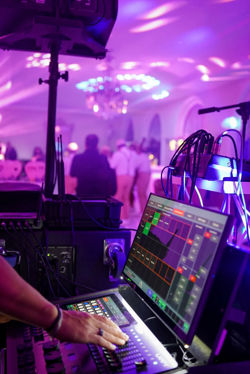 La mano del tecnico sulla console luci, la sala viola che balla sullo sfondo